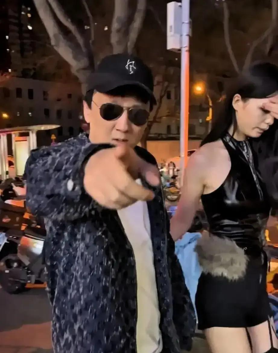 假思聪在新天地街头直播，一身西装墨镜，身边围着助理，拎着大牌购物袋摆拍。
路人拿