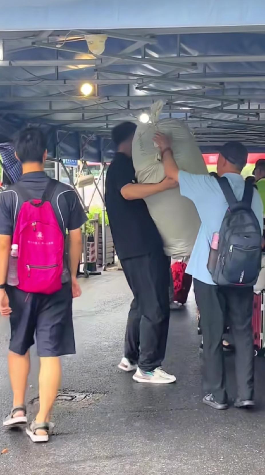大学新生报到的人群中，一个扛着蛇皮袋的黑衣男孩，走过来的身影，让路人看着直呼赞佩