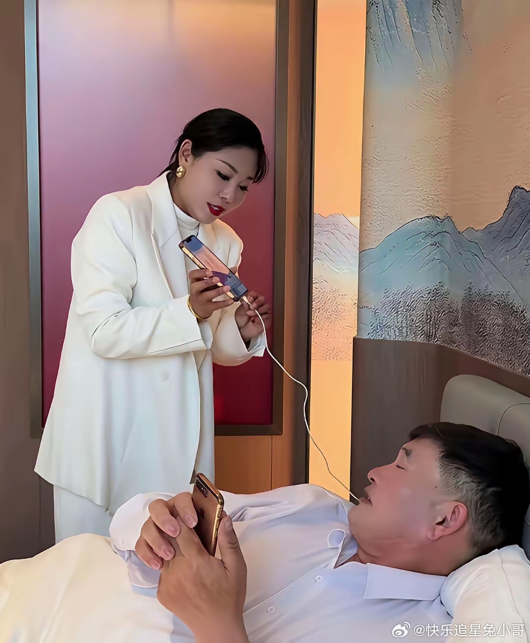 大衣哥外出演出入住酒店时，演出团队的一位美女工作人员在帮他调试手机、对接直播相关