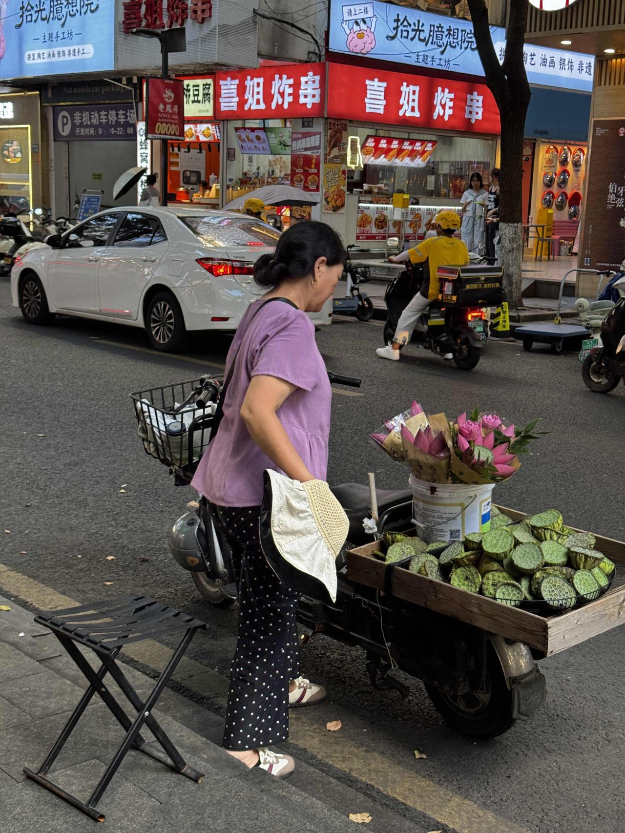 记录生活，随手拍张照苏州街头，阿姨骑着小车卖荷花莲蓬，绿蓬粉花一车清凉，混在炸串