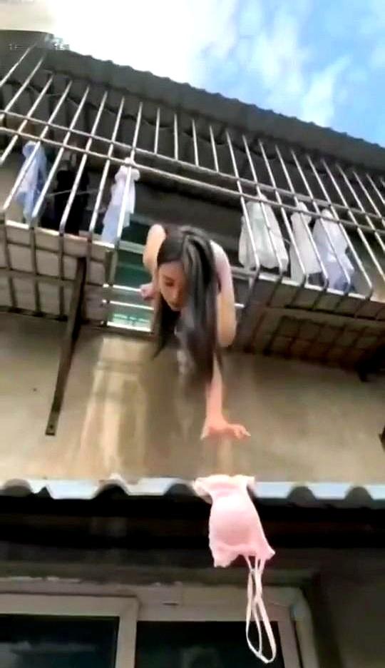 阳台上收个衣服，结果一件内衣掉到窗户顶棚上，美女一着急，半个身子探出去够。
谁能