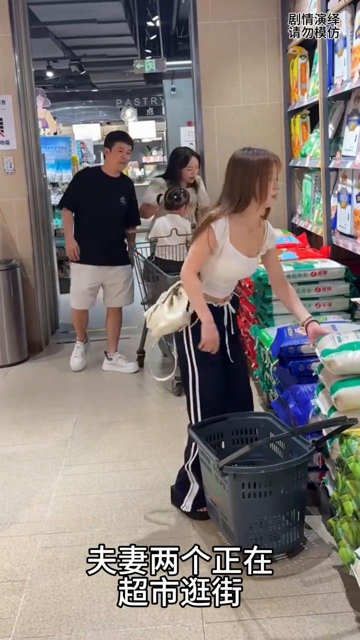 夫妻两个正在超市逛街，这时丈夫看到女子搬大米太累，于是他赶紧过去帮忙搬大米。女子