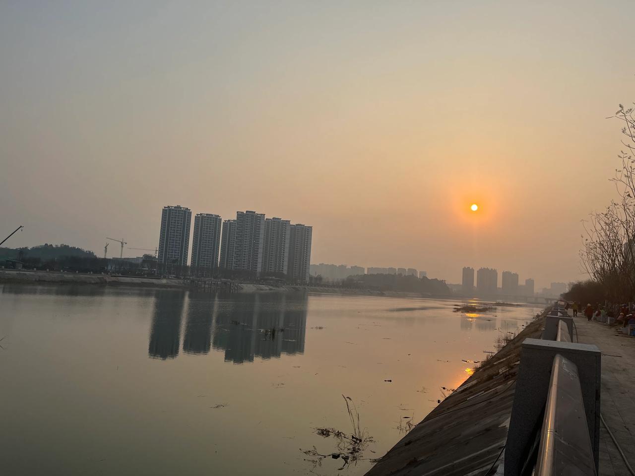 冬日西阳挂远空，凯江东河汇流中。
寒波碎影金鳞闪，风抚余辉映晚红。