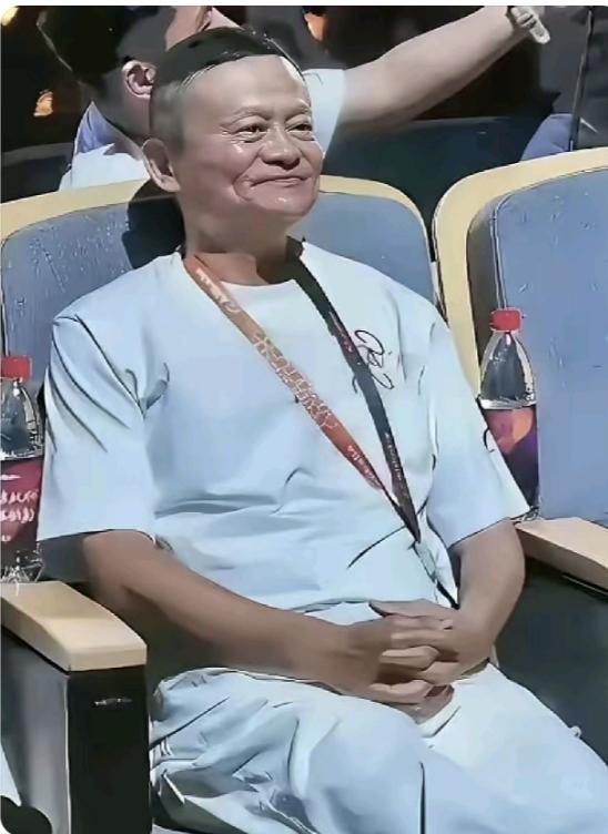 马云今年61岁了，穿着一身浅色衣服，坐在那里，两只手扣在胸前，整个人比年轻时胖了
