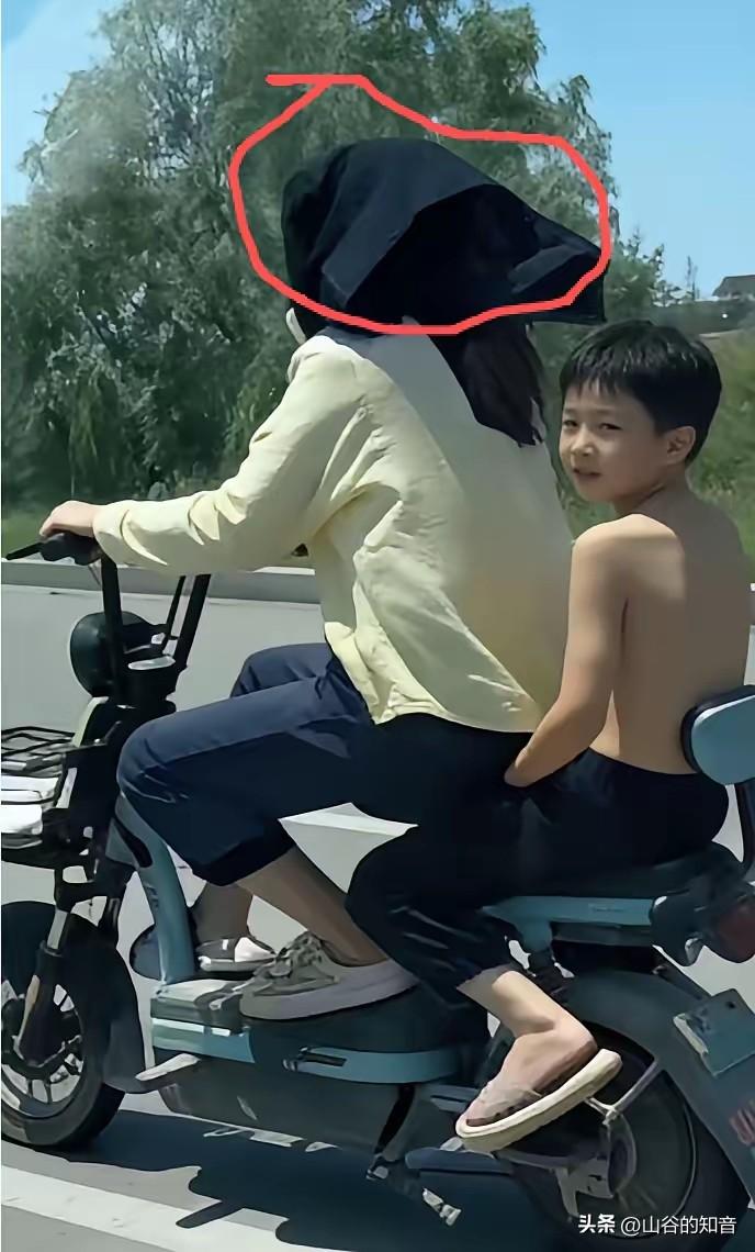 这孩子简直太有孝心了！天气炎热，一位母亲带着孩子出门，可能忘记带了遮阳帽，然后搞