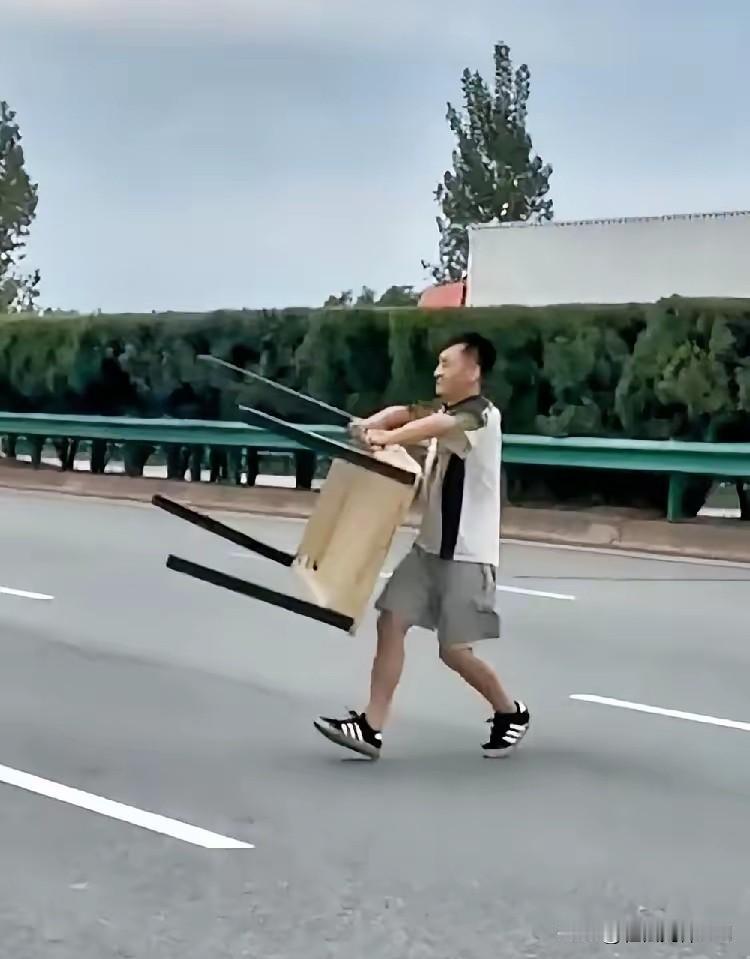 男子站在高速应急车道上，瞅着一辆黑色轿车疾驰而过后，迅速地跑到路中间，弯腰双手抓