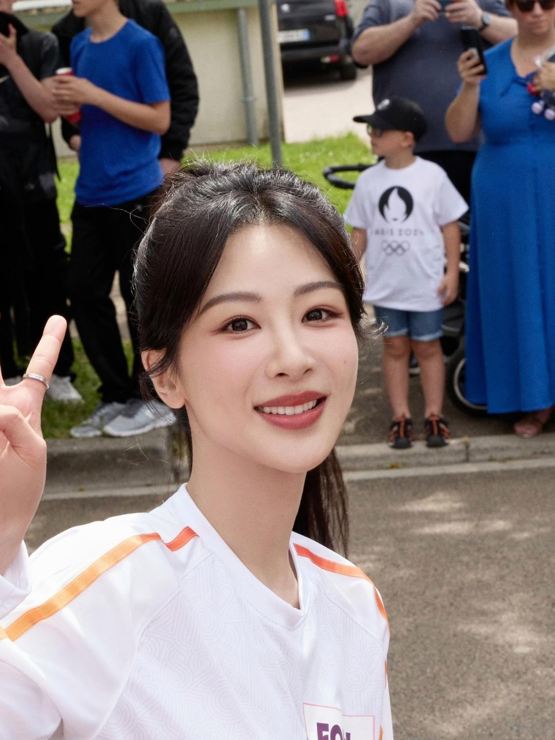杨紫身穿白色运动上衣搭配橙色条纹，胸前“EOYY”及奥运标识格外醒目，高扎马尾清