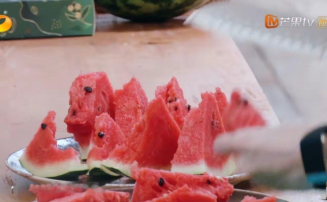 黄晓明徒手劈开两个西瓜，昆凌接着切块分给大伙吃。 
