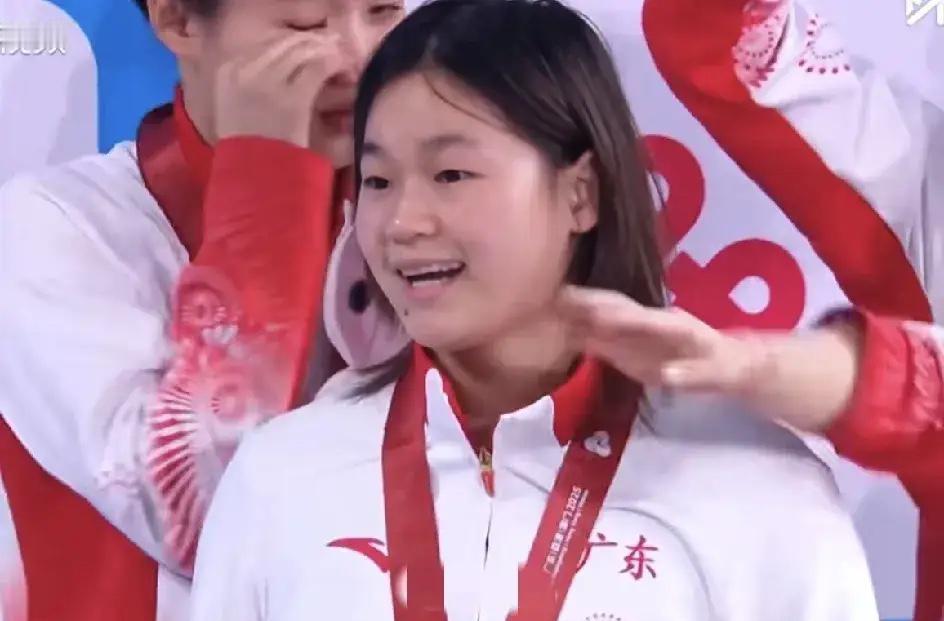 镜头里捕捉到一个打哈欠又紧急撤回的全红婵，还不好意思的嘿嘿笑了。

训练馆的挂钟