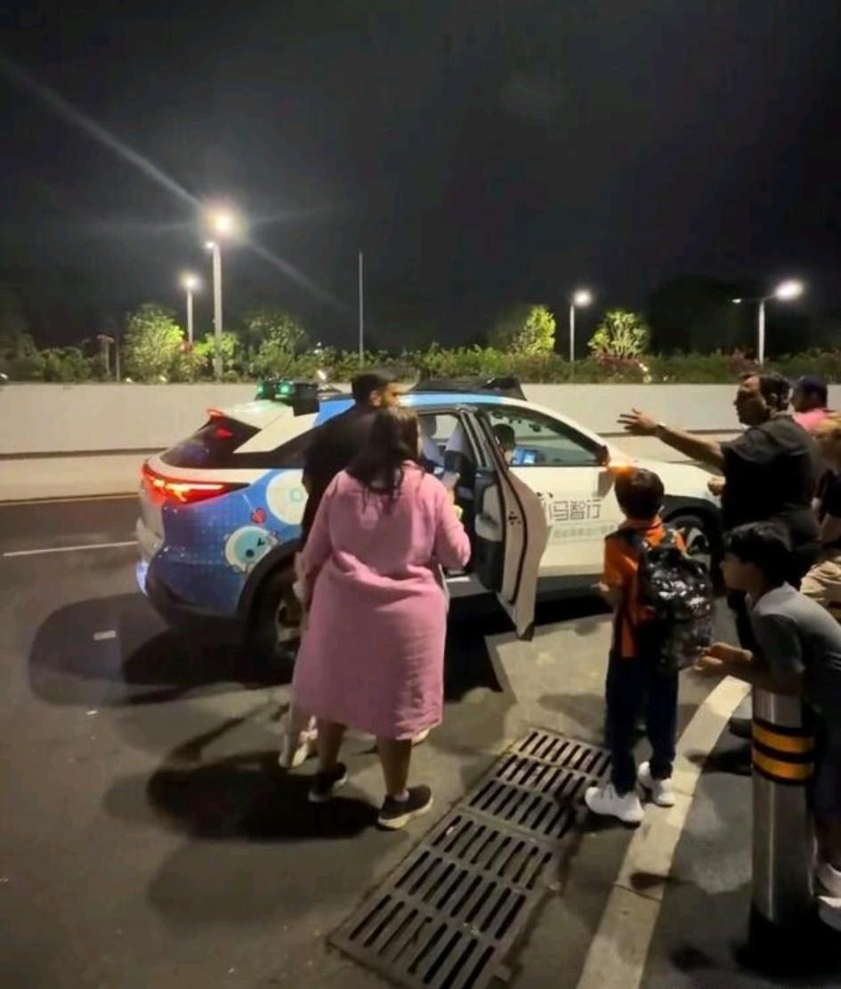 深圳街头，一家八口印度游客正围着一辆无人出租车。他们并非看不懂车，也不是存在语言
