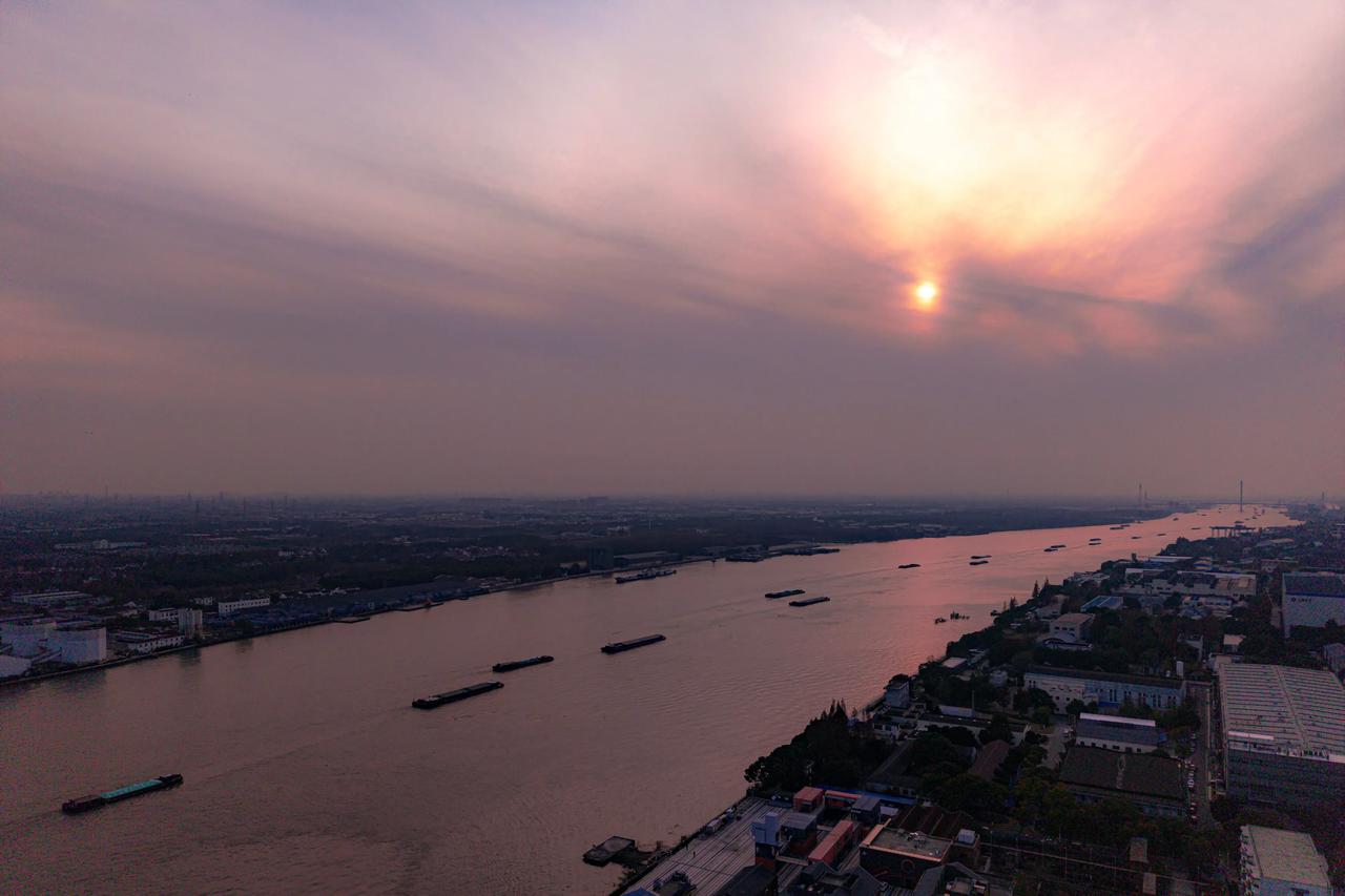 夕阳西下，江面波光粼粼，船只穿梭其中，美景如画。🌅🚢🌊