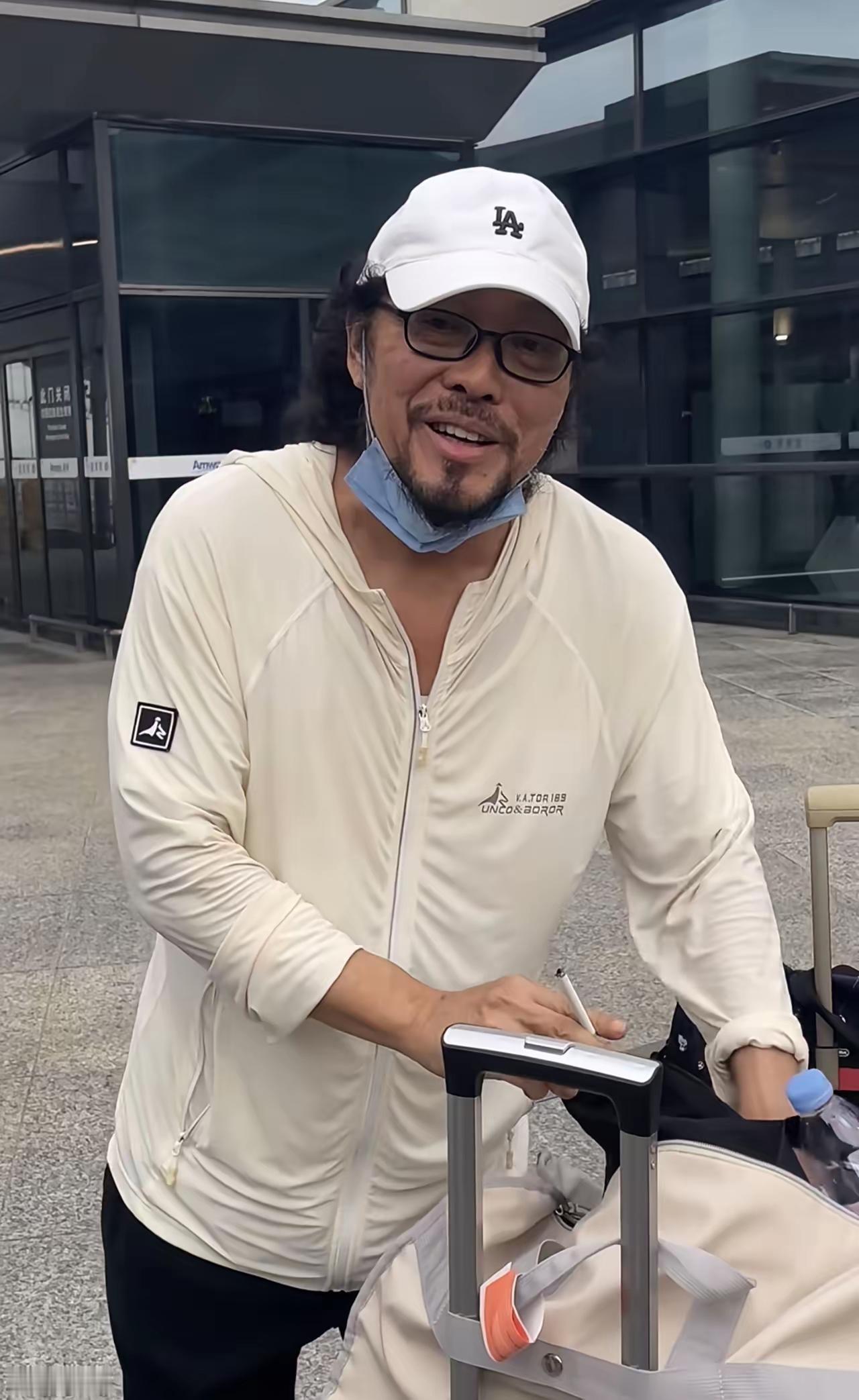 戴帽子的人正在推行李箱。还有人认识他吗？宝岛主持界的扛把子，当年真的很红啊文艺男