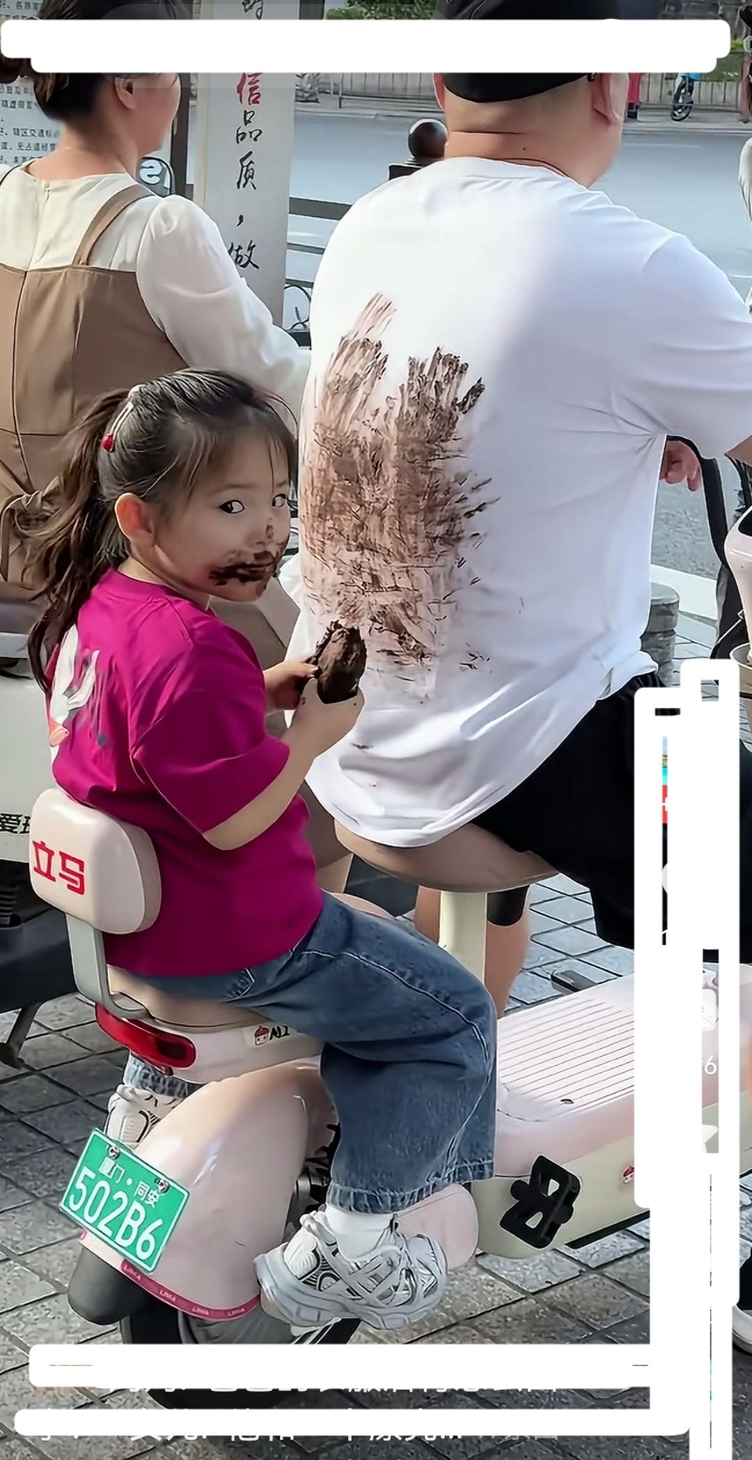 小女孩端坐在父亲的电动车后座，正美滋滋地舔着冰淇淋，接着将沾满冰淇淋的双手往父亲