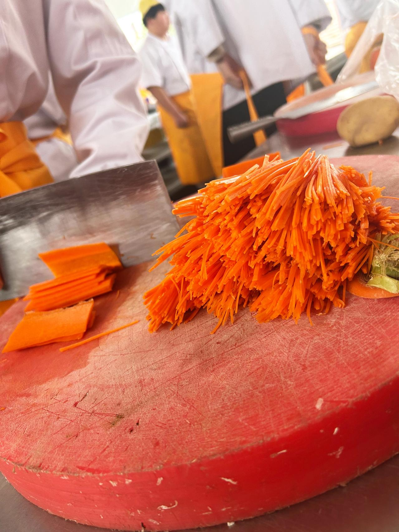 厨房里的快节奏，厨师们齐心协力，将胡萝卜切成细丝，为美食增添色彩。厨师