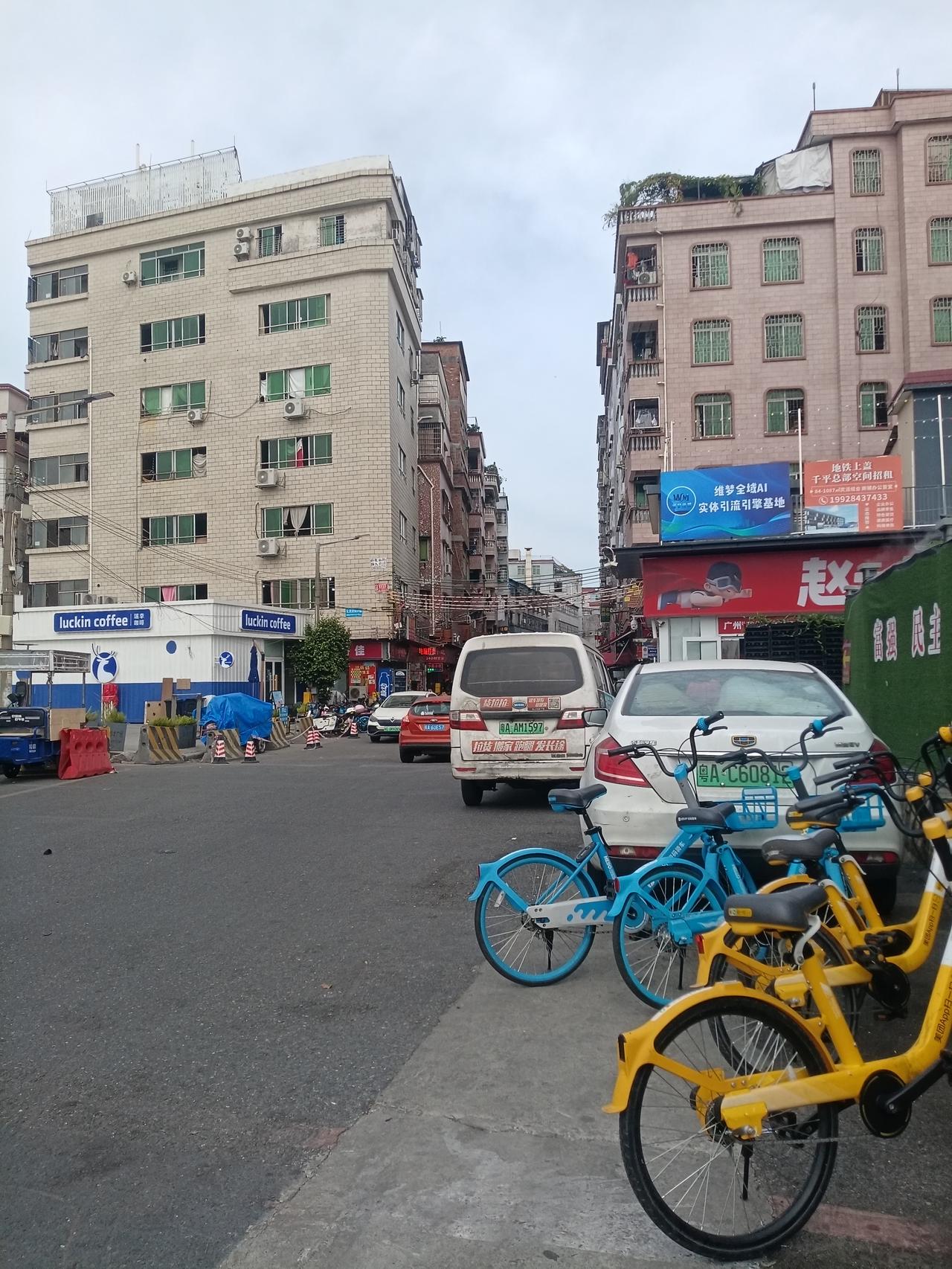 广州海珠区桥南新街街头，街道两旁都是七八层公寓楼和出租房，还有厂房，道路上停满了