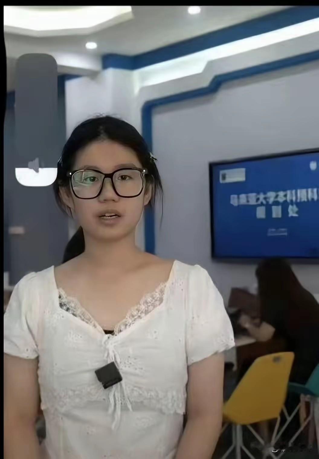 这位小仙女，很快要出去留学了，后面屏幕上的文字应该就是要去留学的学校，就是看不太