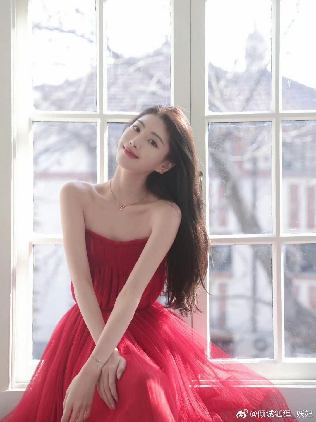 窗边红衣少女，温柔微笑，阳光洒落，美如画卷。