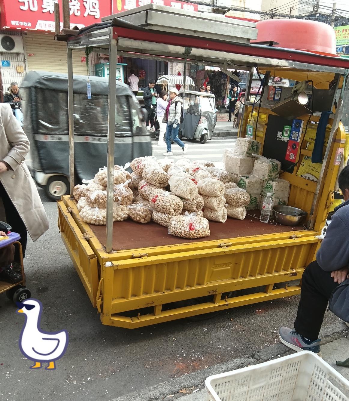 “大姐，这花生咋卖啊？”带娃的大姐推着小车凑近问。摊主抬抬眼：“十块钱三斤，刚炒