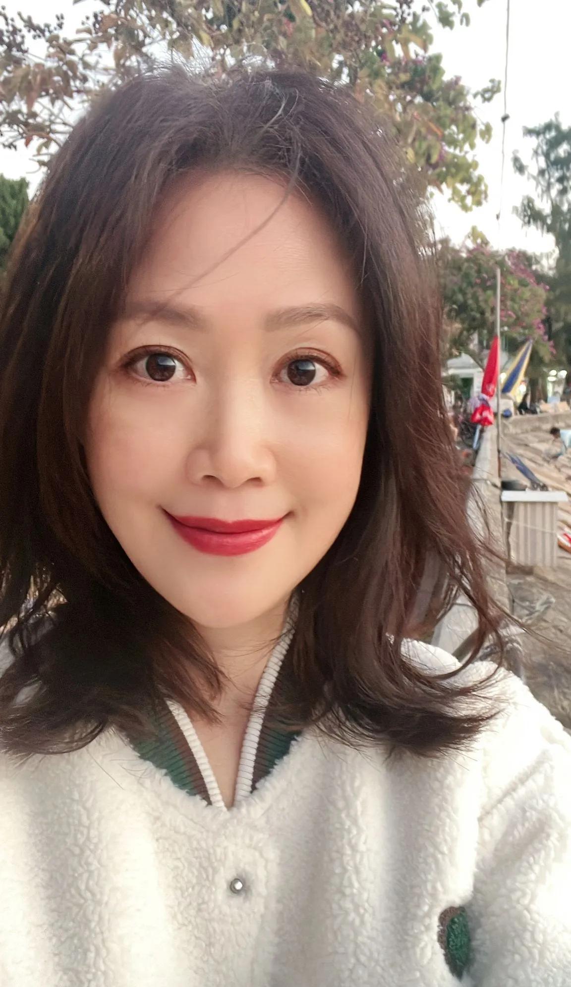 梁小冰晒外出游玩照，54岁美丽依旧！照片中，梁小冰身穿白色外滩搭配白色长裙，温柔