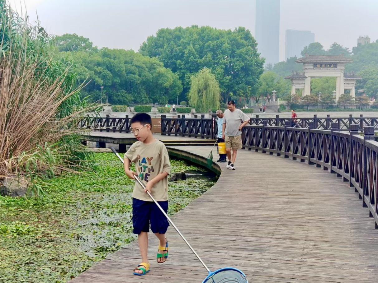 旅行随手拍闷热的夏天，漫步湖边木栈道。拿着渔网玩水嬉戏，大人陪着孩子，简单的陪伴