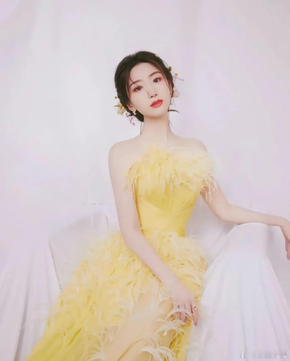 毛晓彤以精致盘发点缀甜美气质，一袭柠檬黄抹胸羽毛拖地连衣裙轻盈垂坠，羽毛摇曳间，