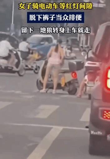 等红灯时竟直接在路边脱裤小便！一名女子骑车等红灯期间，突然就在路旁就地解决，随后