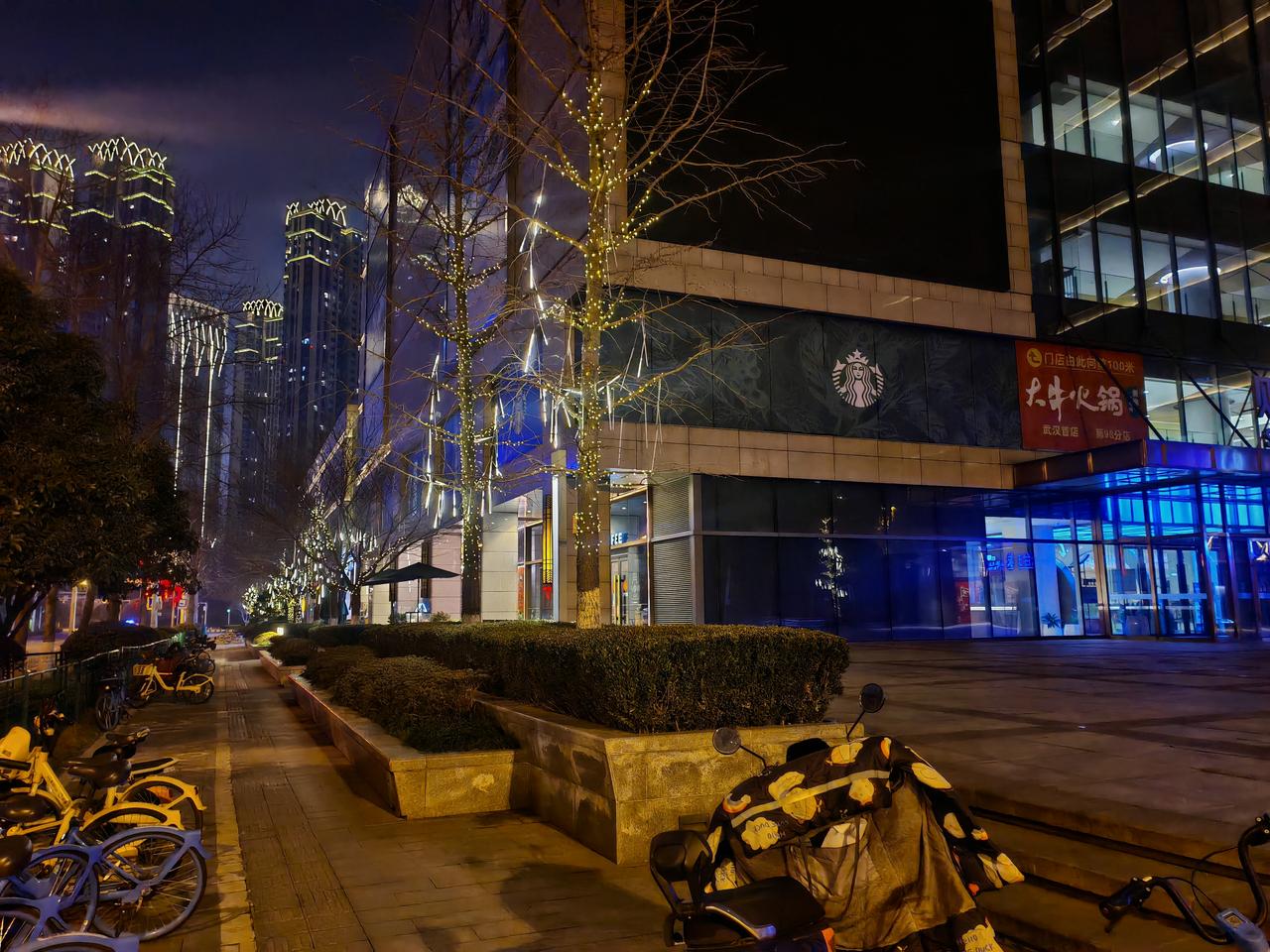 分享一张最近随手拍的照片夜色笼罩城市街道，路灯洒下柔和光晕，高楼楼宇灯带璀璨夺目