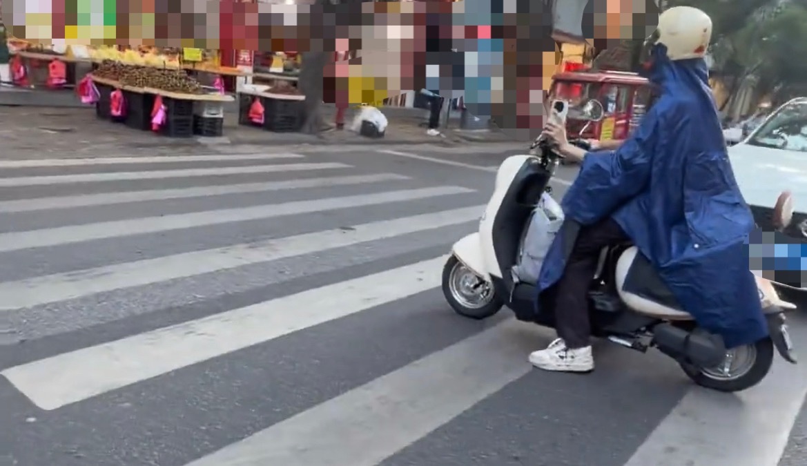 近日，玉林城区一男子骑电动车穿雨衣防晒，这是怕晒黑了吗？还是不知道热？ 玉林