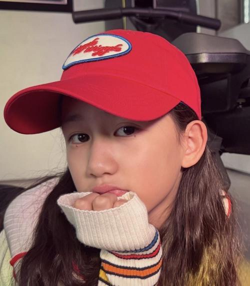 孙莉晒出的二女儿黄少艾日常里，小姑娘趴在书桌前攥着笔歪头琢磨写话，鬓角碎发被风吹