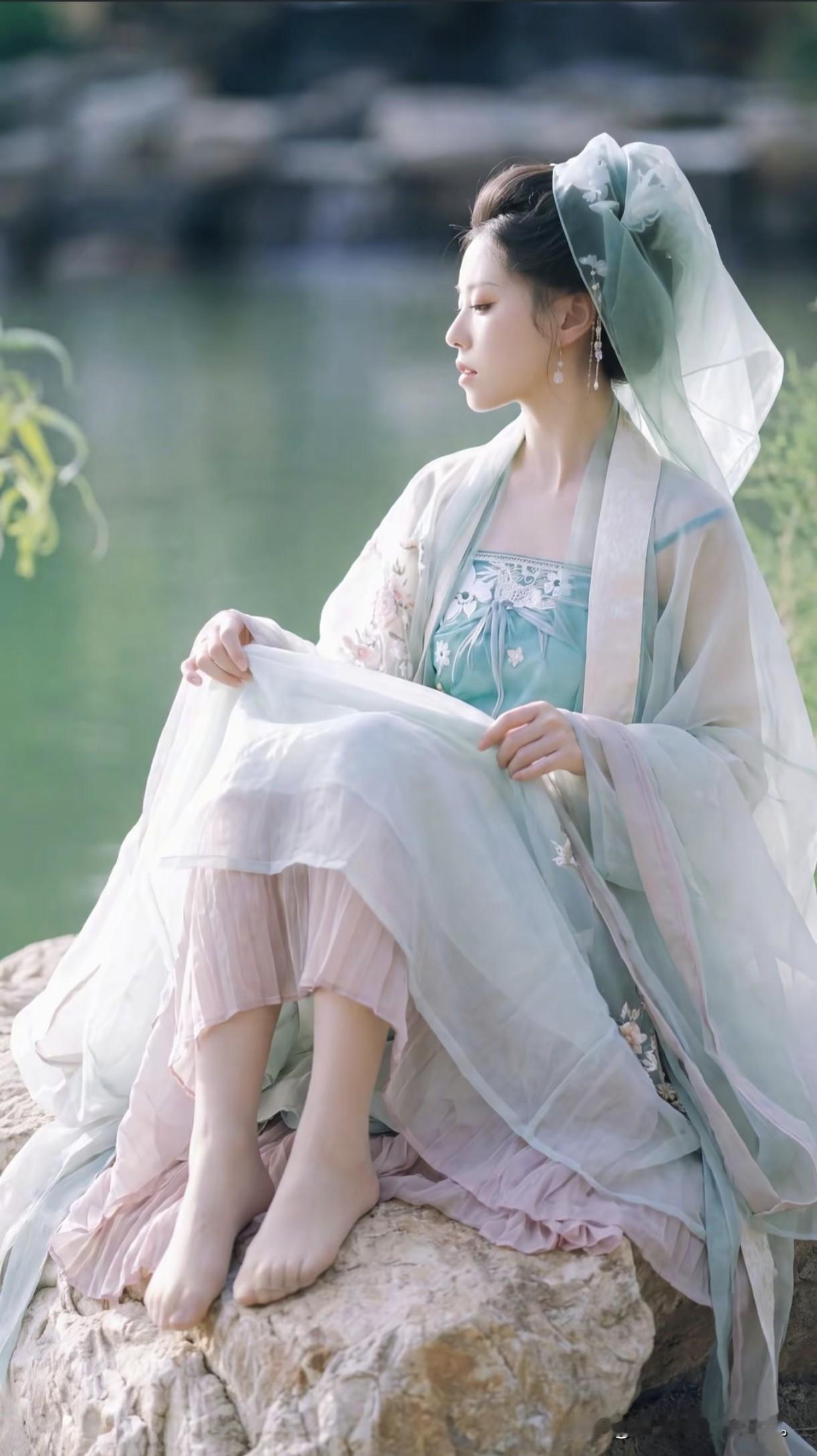 一袭青绿汉服，轻纱曼舞，
像是从曹植笔下走出的洛神。
身畔是碧波荡漾的湖水，
身