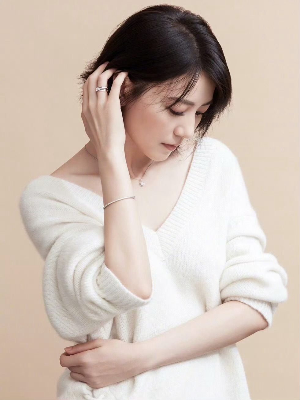 身着宽松白衫，低眉抬腕的姿态温柔又克制。简约银饰点缀其间，与柔和的光影交融，既流