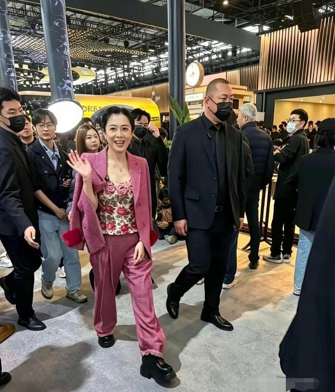 甘比现身上海某大型展会现场，全程笑容亲切随和，完全没有端起豪门阔太的架子。她身穿