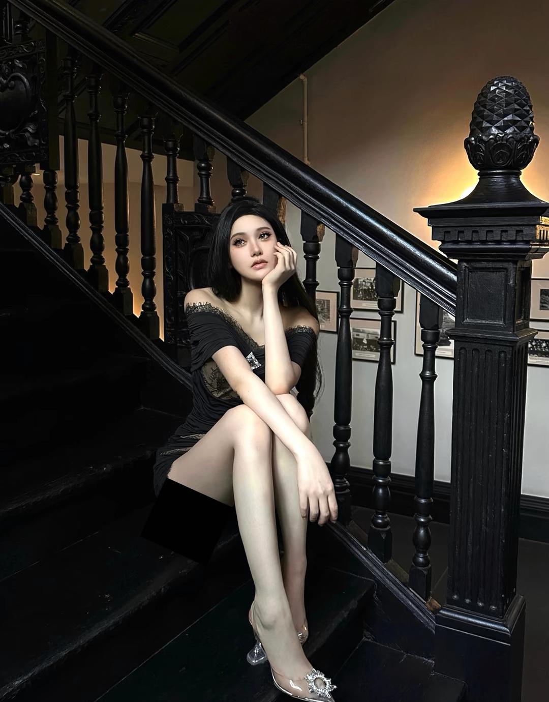 优雅黑裙少女，静坐古朴楼梯，尽显复古韵味。