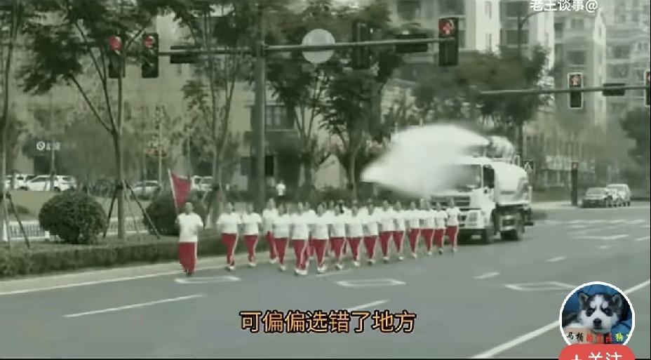 一队健走队占着马路中央大步前行，把后面的洒水车死死挡住，司机连连鸣笛示意避让，队