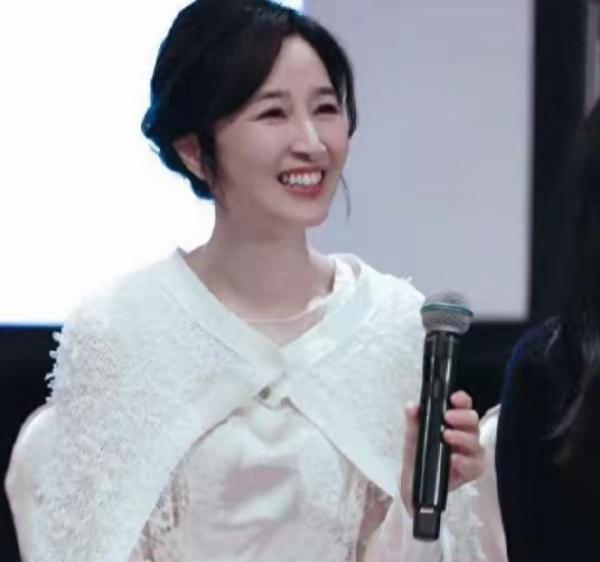 这位女士拿着麦克风，面带微笑。60多岁了依然美丽。还有人记得她吗？非常低调的一位