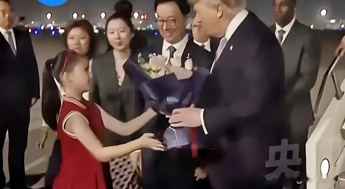 整个接机仪式中最引人注目的就是那个穿红色连衣裙的小姑娘，手里捧着花，在满是黑压压