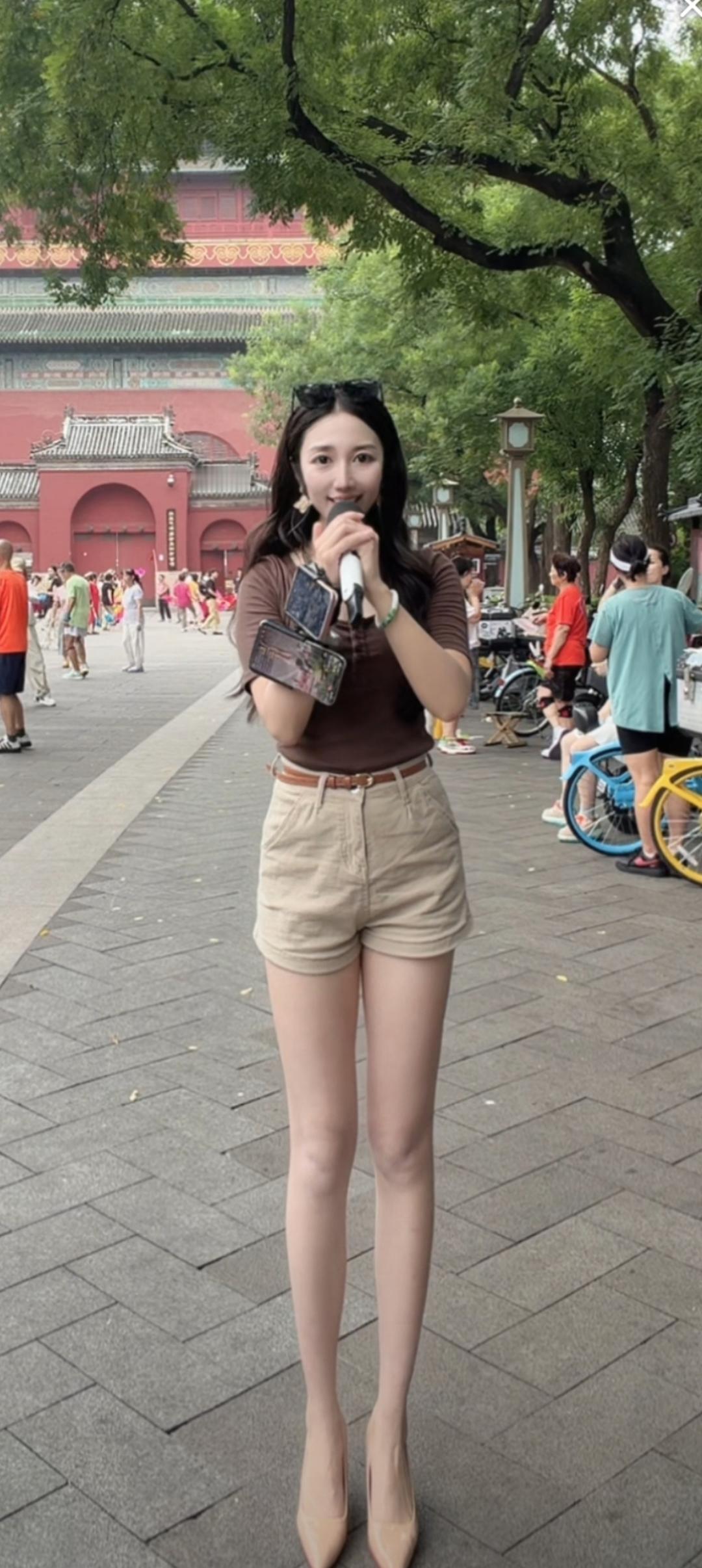一个女孩在景点自拍，背景有游客。