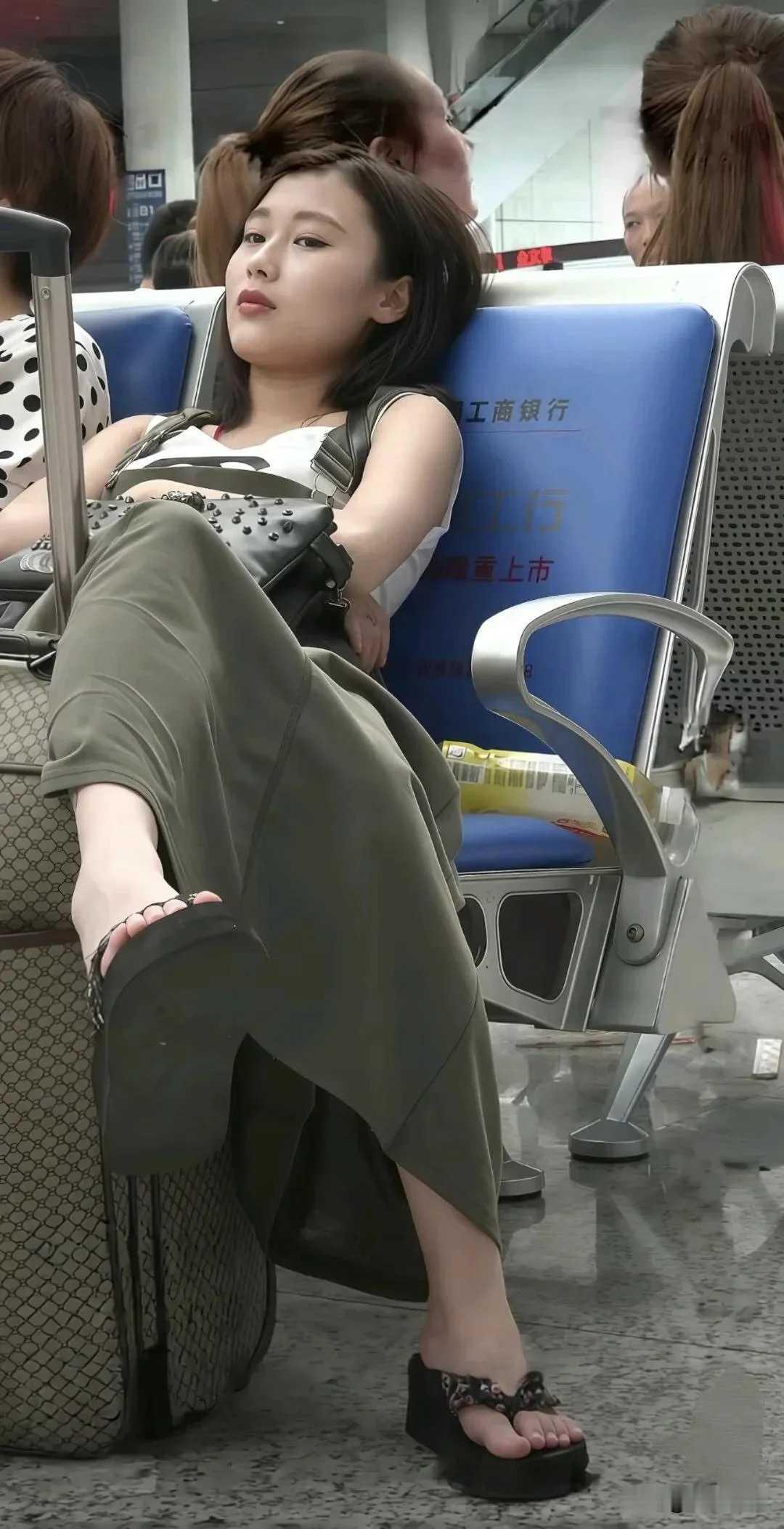 姑娘坐姿虽然不雅观，但是脚可真白呀，脸蛋也很标志。不过出门在外，还是要多注意形象