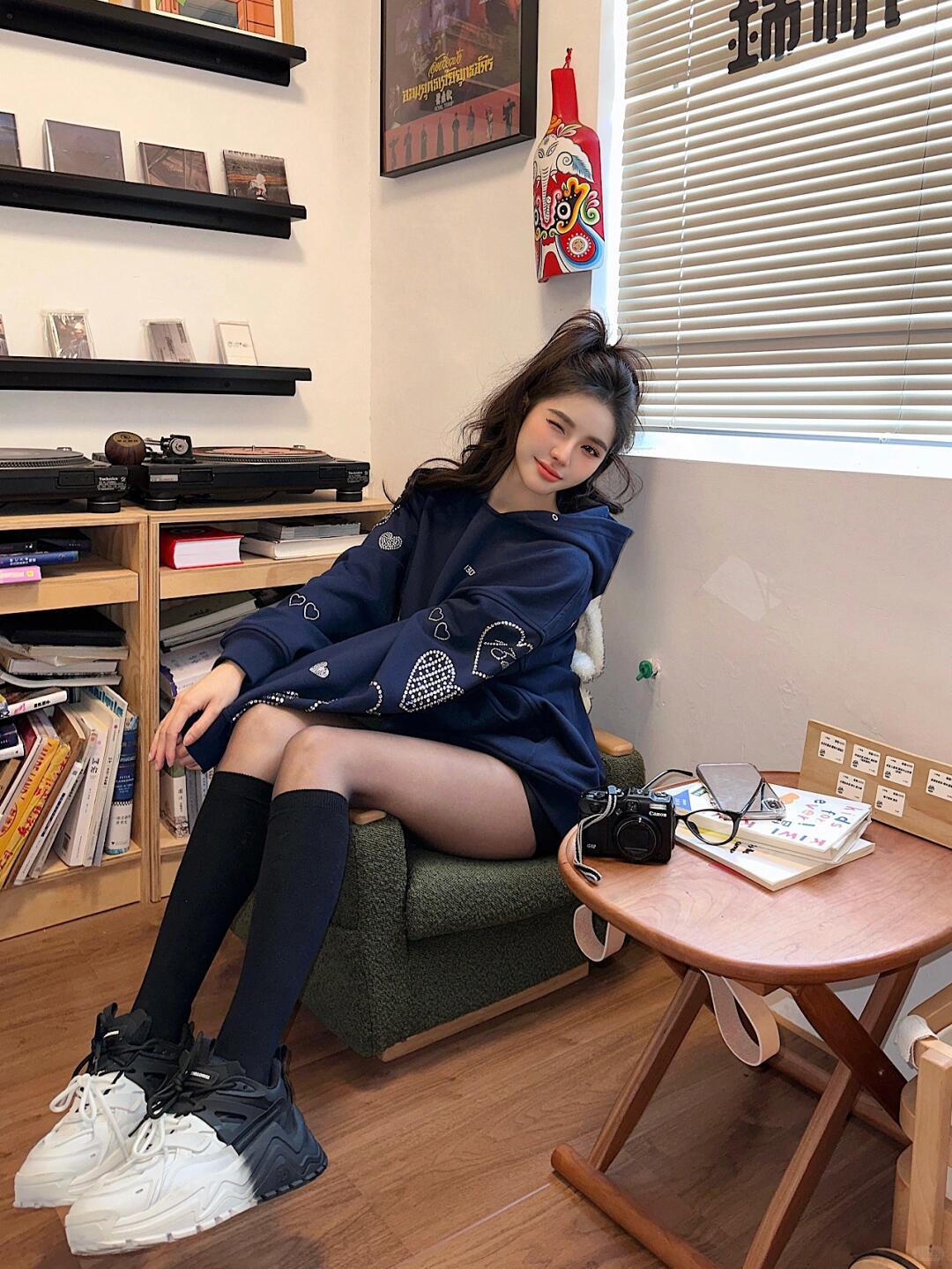 卫衣搭配黑丝袜，这组合把简约时尚发挥到极致。宽松深蓝色外套下摆过臀线，搭配微透黑
