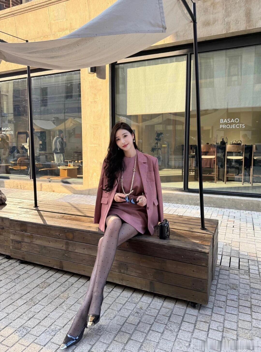 一身干枯玫瑰色粗花呢套装是造型的核心：无袖收腰连衣裙搭配同色系西装外套，宽腰带勾