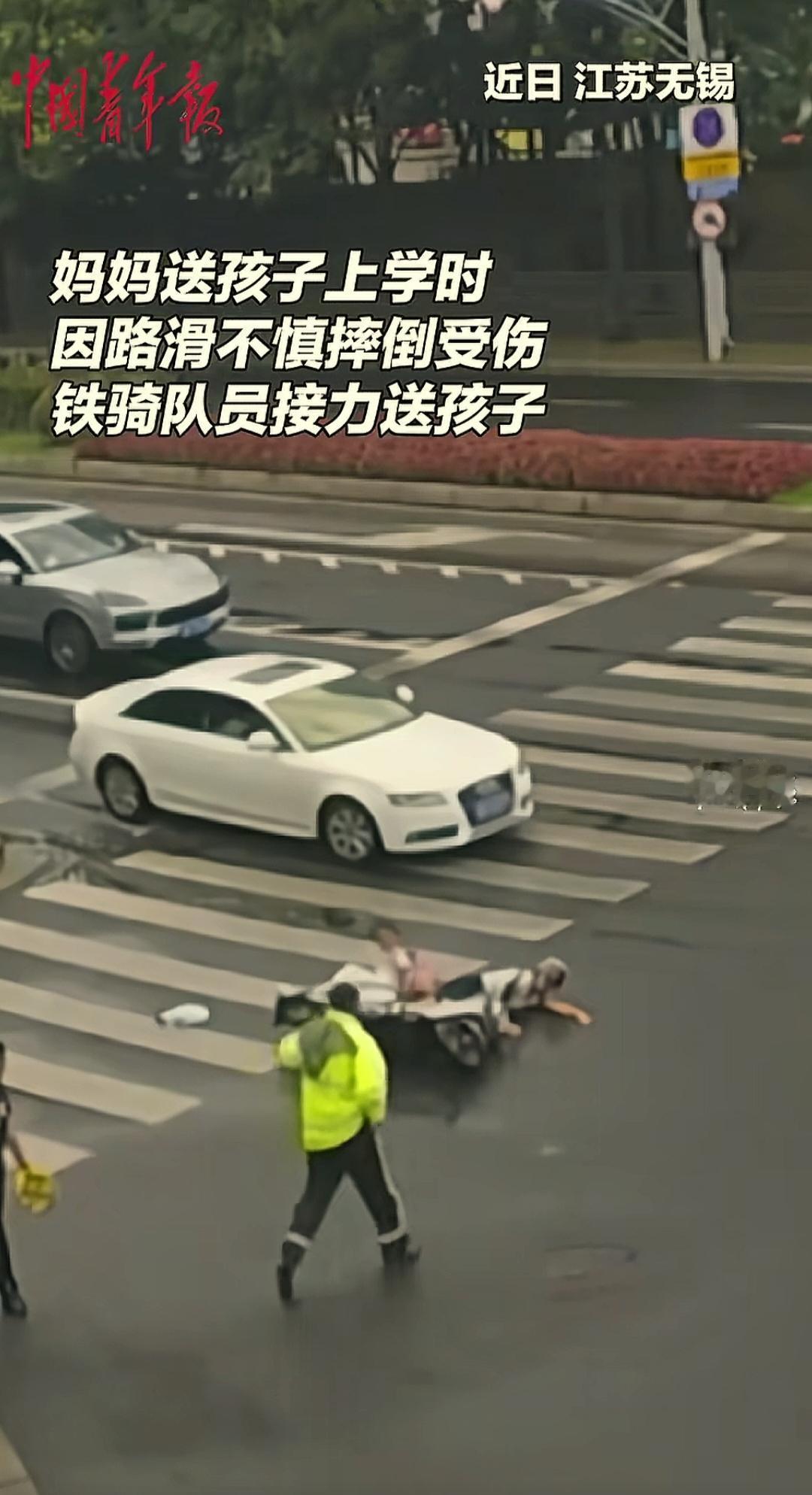 江苏无锡街头，下过雨的地面湿漉漉的，一女子用电瓶车载女儿去学校，在斑马线上不慎摔