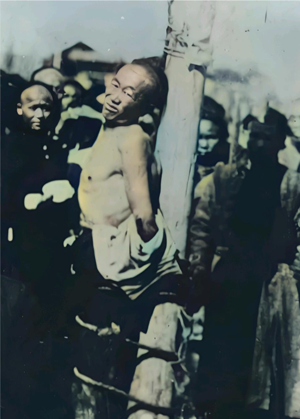 1905年初，一名犯人被剥去上衣绑在柱子上，旁边一群人围着看热闹，这是清朝末期的
