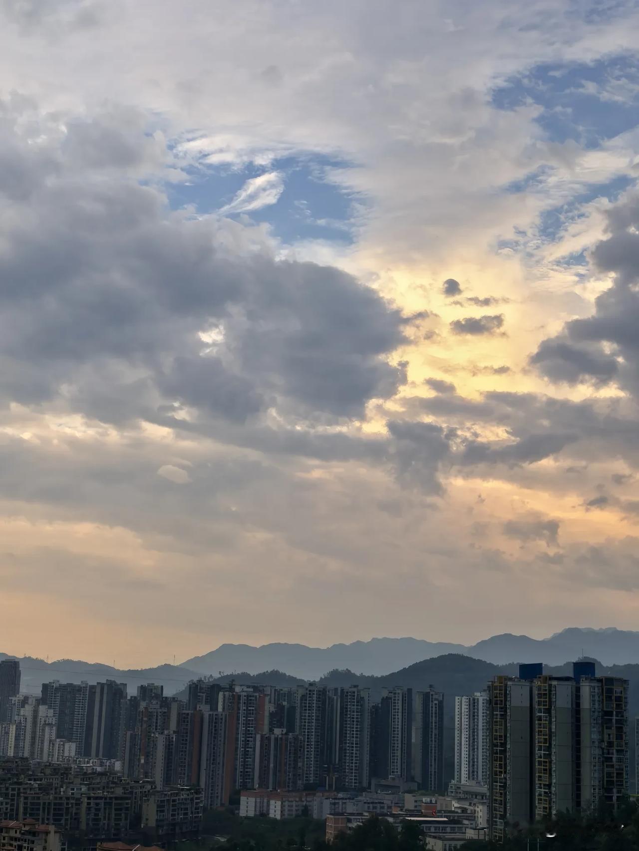 落日余晖冲破厚重的云层，给林立的高楼镀上一层璀璨的金边。远处的群山如黛，钢铁森林