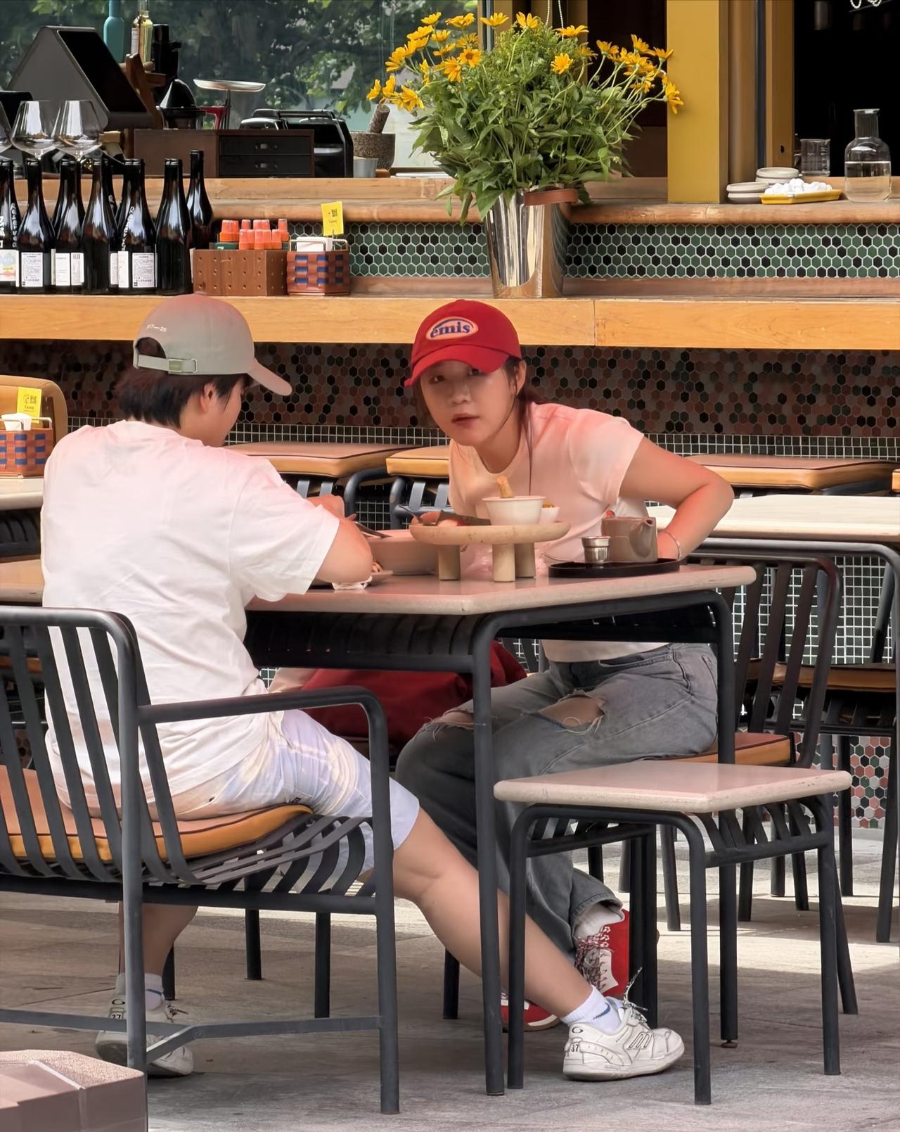 陈梦与王艺迪坐在三里屯一家餐厅外用餐，
陈梦戴红色棒球帽，
穿粉色短袖，破洞牛裤
