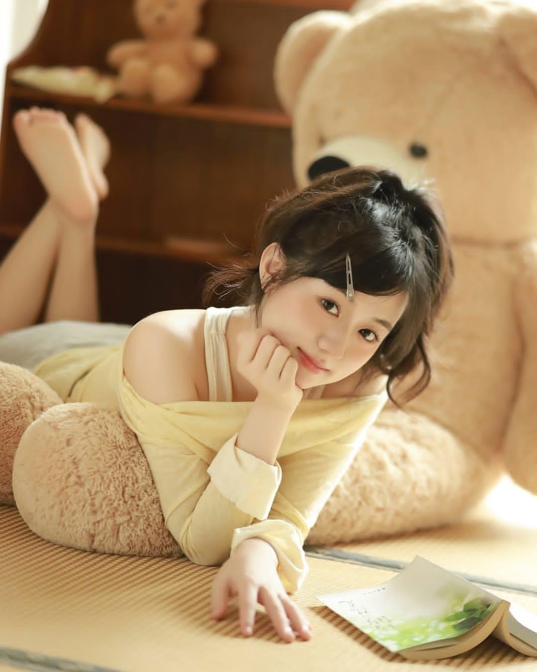 女孩躺在地上，靠着大熊玩偶。