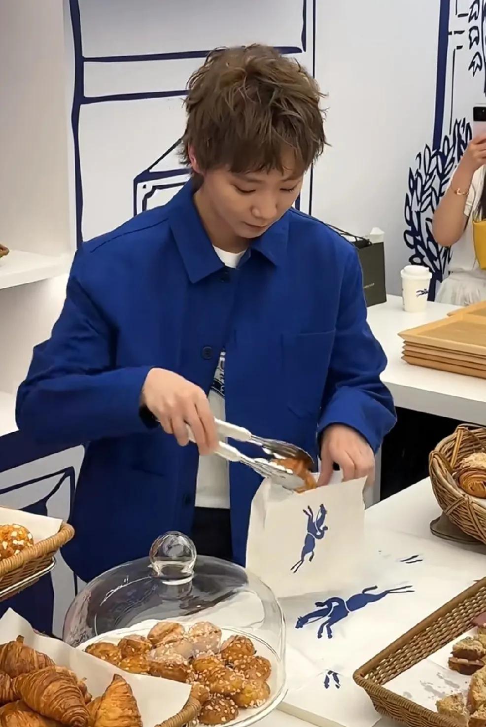 王曼昱今天现身面包店了，
眼前的牛角包你们想不想吃一个呢？
装完面包以为是要签名