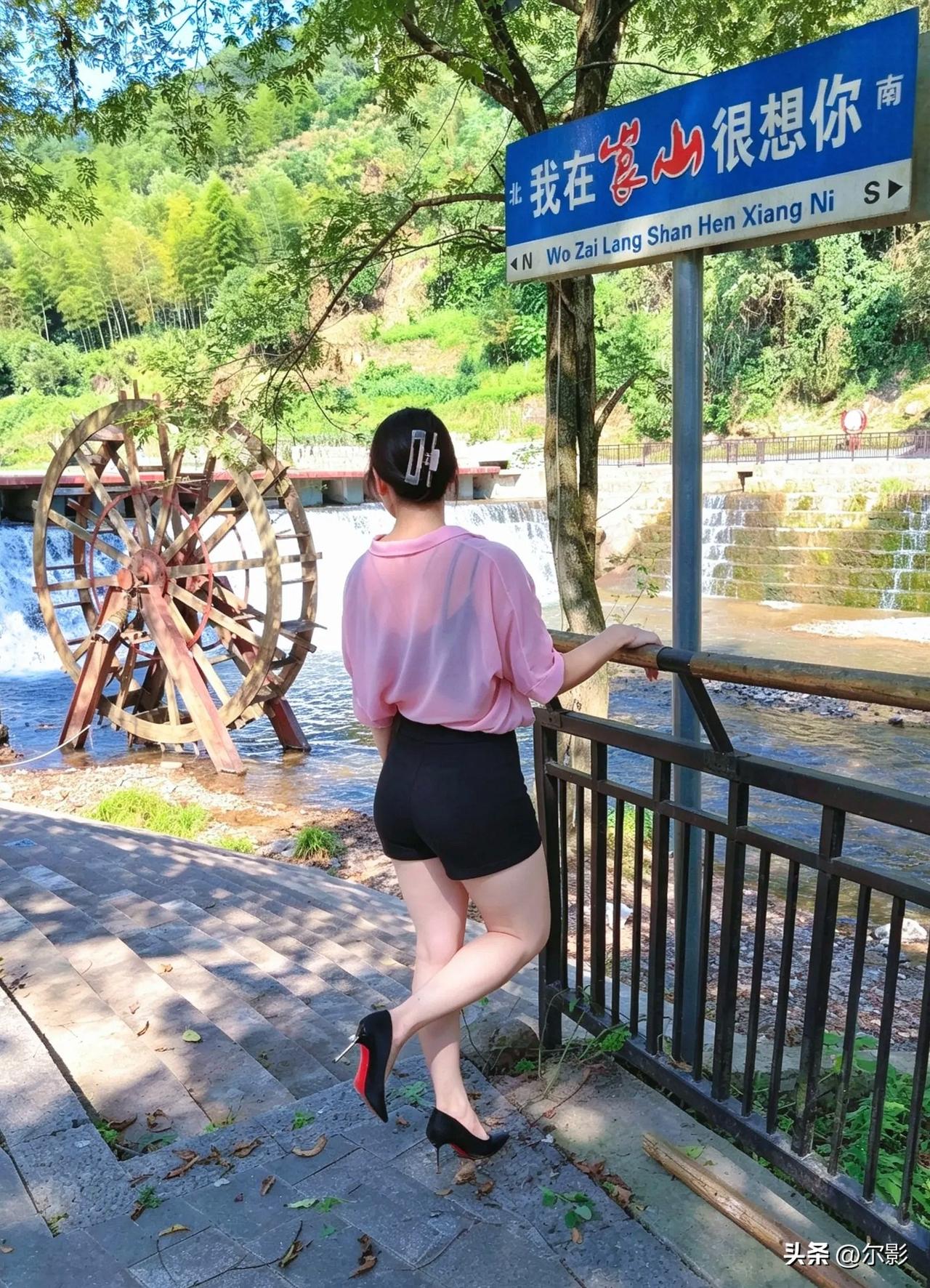 红衣短裤步溪边，夹绾青丝不露颜。高跟轻点背身立，流水潺潺入镜间。