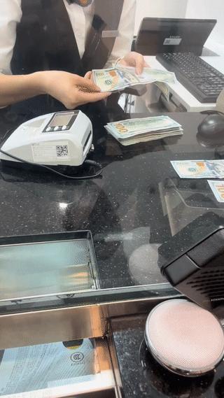 男子去银行用美元兑换人民币，银行工作人员看到男子拿来的美元钞票显得非常的谨慎小心