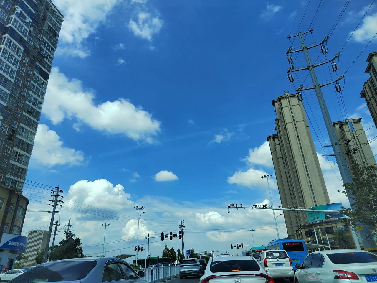 蓝天白云下的城市街景就像一幅流动的画卷。澄澈蓝天搭配棉花糖似的白云，诗意满满。高