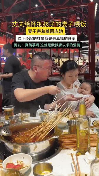 火锅店里，妻子抱着孩子腾不出手吃饭，丈夫便拿起串串细心喂她，还帮她擦嘴。

妻子